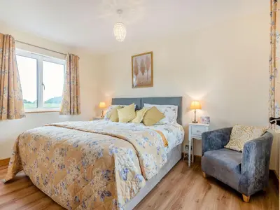 a bedroom with a bed and a blue chair at Violet Cottage in Hereford