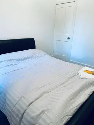 a bed with a white sheets and a door at 21 ,North Street in Shrewsbury