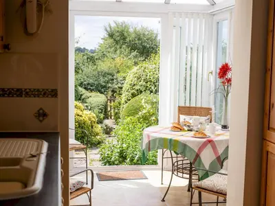 a dining room with a table and a view of a garden at Cosy cottage with views over the Shropshire hills - Pass the Keys in Ludlow