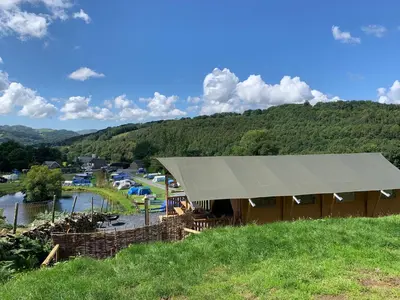 a tent on a hill with a view of a river at Mountain View Safari Tent with Hot Tub in The Heart of Snowdonia in Dolgellau