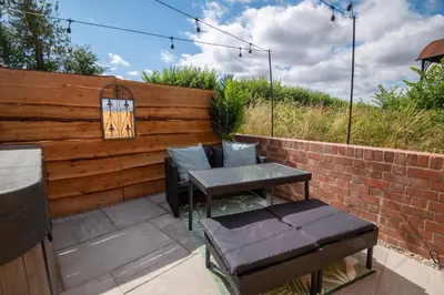 a patio with a table and chairs and a brick wall at Apple Tree Cottage - Cosy 2 Bed with Deluxe HOT TUB & Log Burner in Hereford