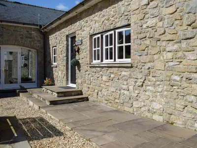 a stone building with stairs leading to a window at Dairy Cottage in Talley
