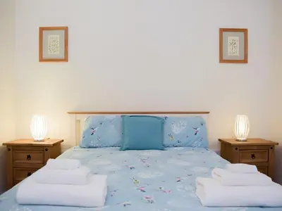 a bedroom with a blue bed with towels on it at Dairy Cottage in Talley