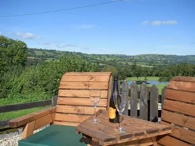 a wooden table with two glasses of wine on it at Dairy Cottage in Talley
