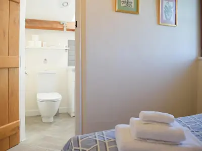 a bathroom with a toilet and towels on a bed at Barn Cottage in Talley