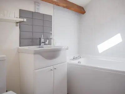 a white bathroom with a sink and a tub at Barn Cottage in Talley