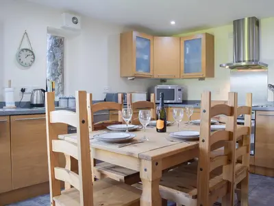a kitchen with a wooden table with wine glasses at Barn Cottage in Talley