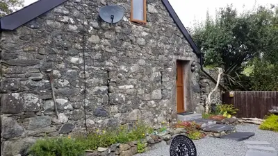 an old stone house with a door and a yard at Yr Hen Beudy in Tywyn
