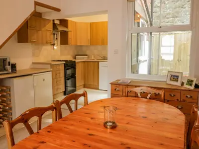 a kitchen with a wooden table with chairs and a window at 4 Tanyrallt Terrace in Llangollen