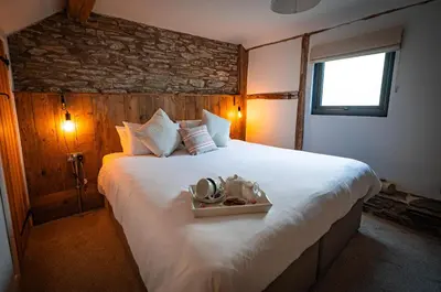 a bedroom with a large white bed with a stone wall at Hay Barn, Penrheol Farm, Unique Barn Conversion in Builth Wells