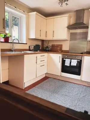 a kitchen with white cabinets and a sink and a stove at Boutique country hideaway ‘Jacks Cottage’ in Diddlebury