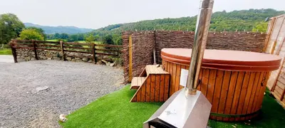 a large barrel sitting on the grass next to a fence at Cader Mountain View Cottage with Hot Tub in Snowdonia in Dolgellau