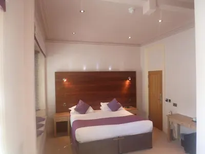 a bedroom with a large bed with a wooden headboard at Castle Hotel in Aberystwyth