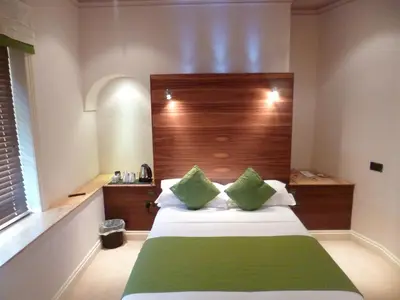 a bedroom with a bed with green and white pillows at Castle Hotel in Aberystwyth