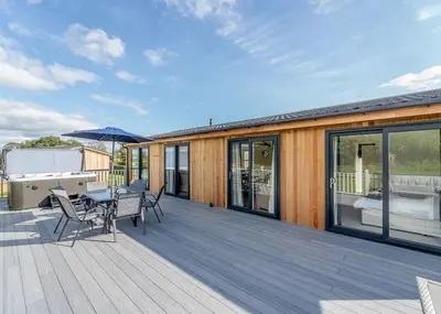a wooden deck with a table and chairs on it at Winston Farm Lodges in Ternhill