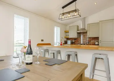 a kitchen with a wooden table with a bottle of wine at Winston Farm Lodges in Ternhill