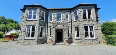 an old stone house with a front door and windows at Cader en suite at Pen Y Coed Hall exclusive Luxury Hot Tub in Dolgellau