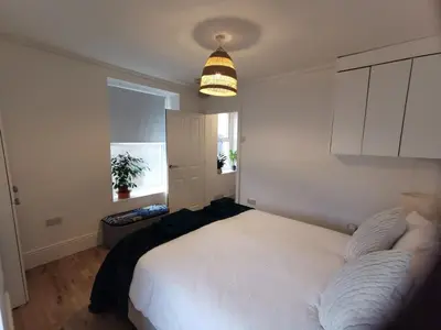 a bedroom with a large white bed and a light fixture at Lovely Seafront 2 bed flat in Aberystwyth in Aberystwyth