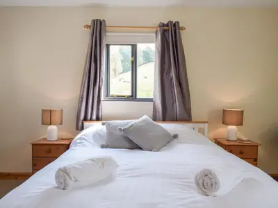 a bedroom with a white bed with two lamps and a window at Hill View Lodge in Knucklas