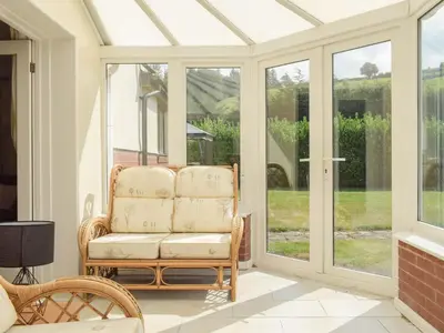 a conservatory with a glass conservatory door with a chair at Hill View Lodge in Knucklas