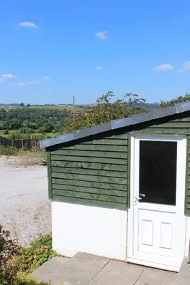 a smallshed with a white door and a window at Poplar Lodge, Dee Valley Stays - cosy microlodge with detached private shower & WC in Corwen