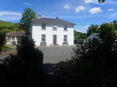 a white house with a driveway in front of it at YR HEN FICERDY in Aberystwyth