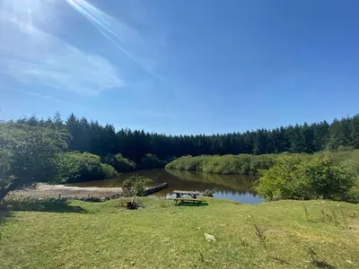 a picnic table in a field next to a river at Lakeside Eco Pod in Oswestry