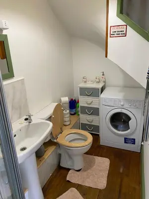 a bathroom with a sink and a toilet and a washing machine at Stable Cottage, Bishops Castle in Bishops Castle