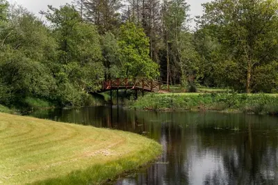 a red bridge over a river in a park at 3 Bed in Aberaeron oc-bow315 in Cross Inn