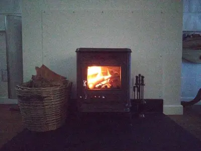 a stove in a living room with a basket at Avryn - Delightful 3 bedroom cottage with stunning vistas in Mainstone