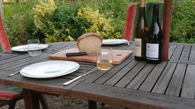 a wooden table with a bottle of wine and glasses at Avryn - Delightful 3 bedroom cottage with stunning vistas in Mainstone