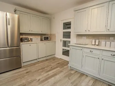 a kitchen with white cabinets and a stainless steel refrigerator at Lleifior in Dolgellau