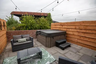 a backyard patio with a grill and a barbecue at Bramble Cottage - Cosy 2 Bed With Deluxe HOT TUB & Log Burner in Hereford