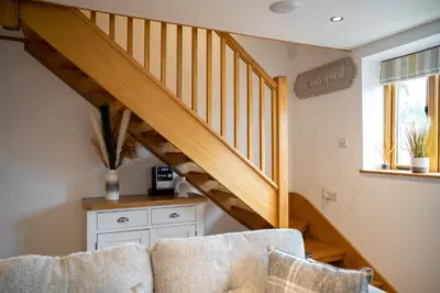 a living room with a couch and a staircase at Bramble Cottage - Cosy 2 Bed With Deluxe HOT TUB & Log Burner in Hereford