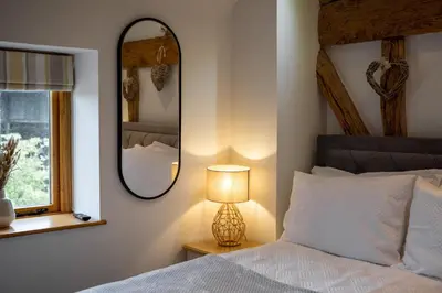 a bedroom with a bed with a lamp and a mirror at Bramble Cottage - Cosy 2 Bed With Deluxe HOT TUB & Log Burner in Hereford