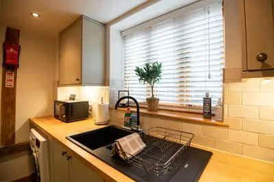 a kitchen sink with a dish drying rack next to a window at Bramble Cottage - Cosy 2 Bed With Deluxe HOT TUB & Log Burner in Hereford