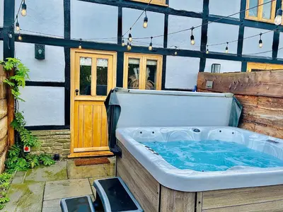 a large bath tub sitting in the back of a house at Bramble Cottage - Cosy 2 Bed With Deluxe HOT TUB & Log Burner in Hereford