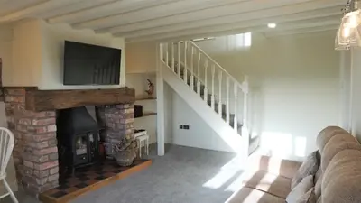 a living room with a fireplace and a flat screen tv at Barley Cottage - 5* Cyfie Farm with log burner and private covered hot tub in Llanfyllin