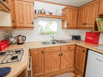 a kitchen with wooden cabinets and a sink and a window at 6 Old Orchard in Much Wenlock