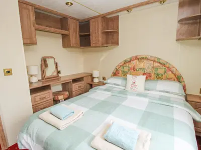 a bedroom with a large bed with wooden cabinets at 10 Old Orchard in Much Wenlock