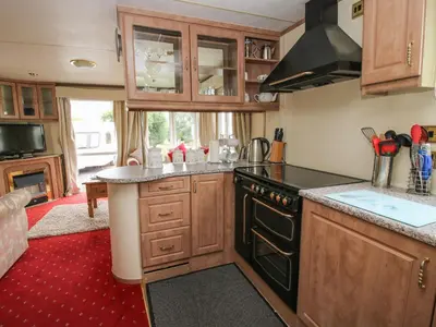 a kitchen with wooden cabinets and a black stove top oven at 10 Old Orchard in Much Wenlock