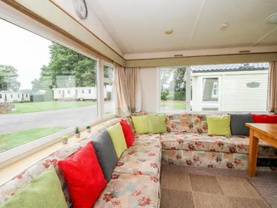 a living room with a couch in front of a window at 3 Old Orchard in Much Wenlock