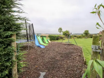 a playground with a bunch of swings in a yard at 3 Old Orchard in Much Wenlock