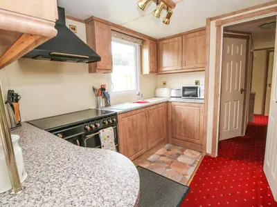 a kitchen with wooden cabinets and a stove top oven at 2 Old Orchard in Much Wenlock