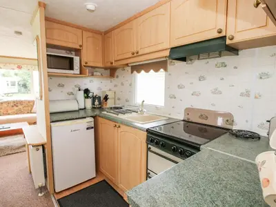 a small kitchen with wooden cabinets and a sink at 9 Old Orchard in Much Wenlock
