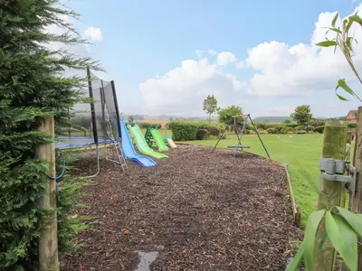 a playground in a garden with a fence at 5 Old Orchard in Much Wenlock