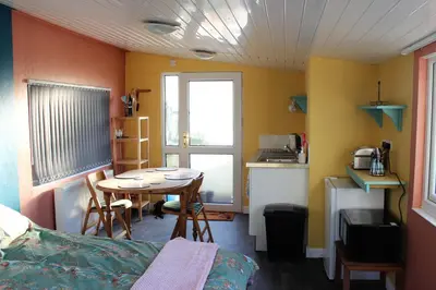 a small room with a table and a kitchen at Redwood Lodge, Dee Valley Stays - cosy microlodge with detached private shower & WC in Corwen
