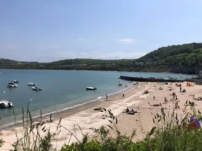a group of people on a beach with boats in the water at Cosy holiday caravan minutes from the beach in Aberystwyth