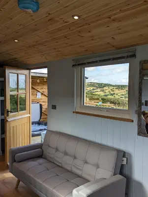 a living room with a couch and a window at Bespoke luxury huts with hot tubs. Located in the black mountains. in Llanveynoe