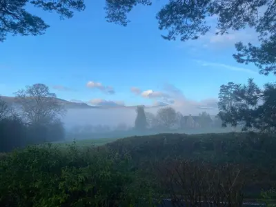 a foggy field with trees and a field with a house at Mountain Suite, Stunning Views, Brecon Beacons in Llanhamlach